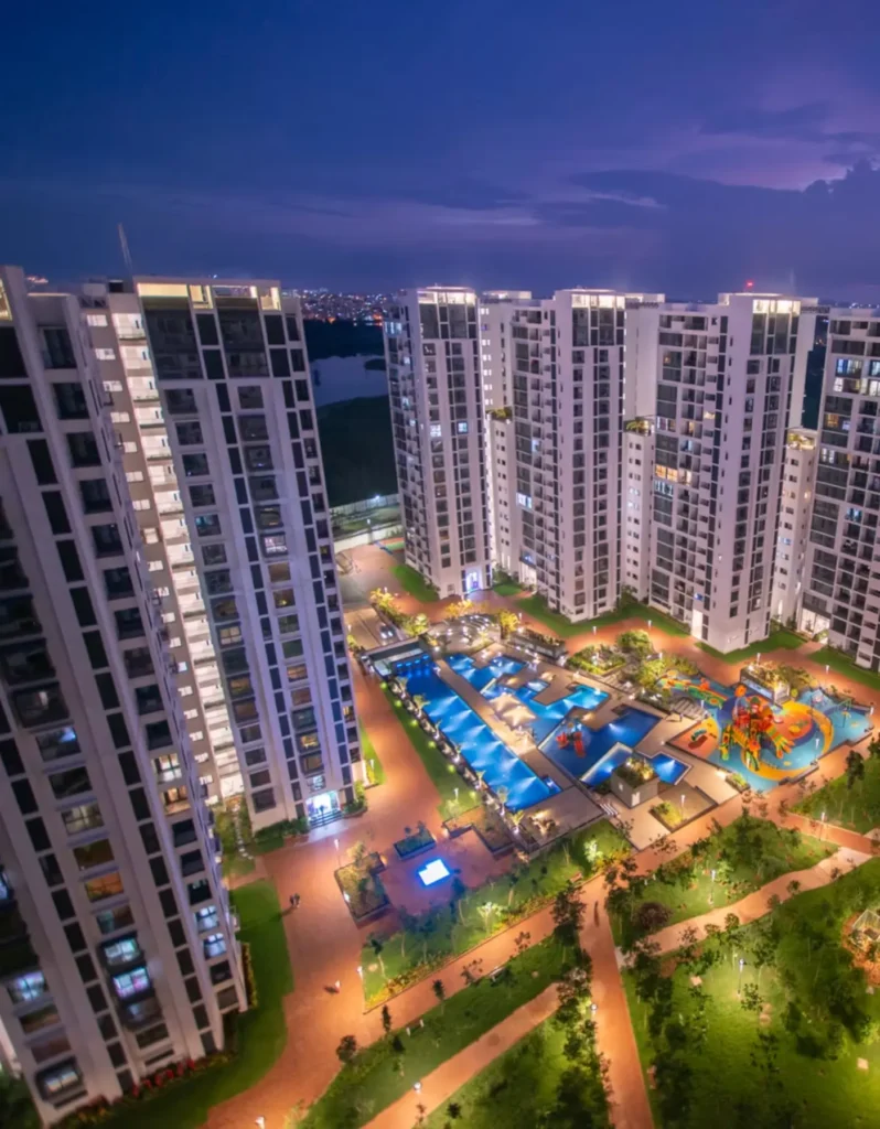 SNN Estates Duomont | A Vibrant Community by Night Aerial night view of SNN Estates Duomont showcasing the illuminated swimming pools, kids play area, and towers.